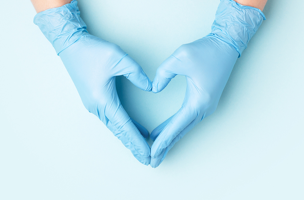 A photo of two surgical hands making a heart-shape